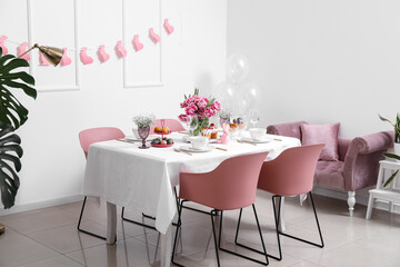 Stylish table setting with beautiful tulips for Easter celebration in room interior