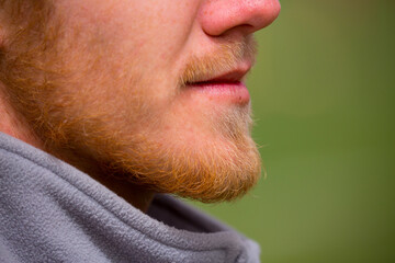 Obraz premium Bearded unshaven man. Close-up of a handsome bearded hipster, elegant man. Bearded man close-up in profile. A man with a growing mustache.