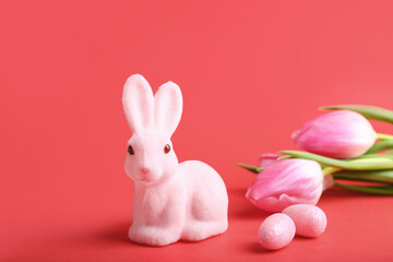 Cute Easter bunny with painted eggs and flowers on red background