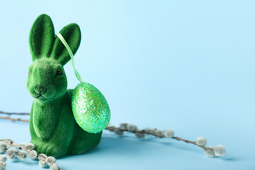 Cute Easter bunny with egg and pussy willow branches on blue background