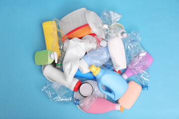 Pile of plastic garbage on light blue background, flat lay