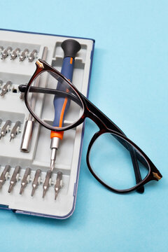 Repair of glasses.Glasses and a screwdriver on a blue background. Eyewear repair tools and accessories. Vertical. Close-up.