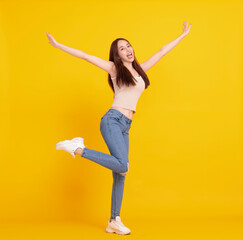 Fototapeta na wymiar Happy young woman jumping and celebrating isolated over yellow