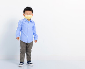 child standing over  white background and wearing face mask