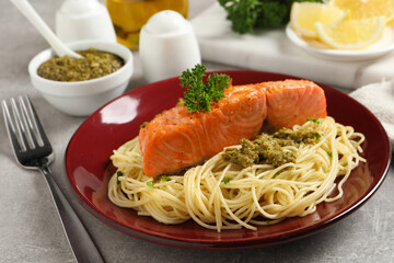 Delicious spaghetti with salmon and pesto sauce on light grey table, closeup