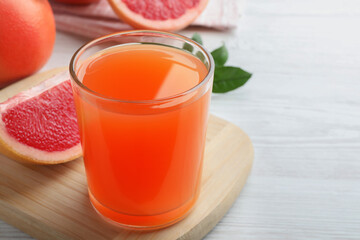 Tasty freshly made grapefruit juice on white wooden table. Space for text