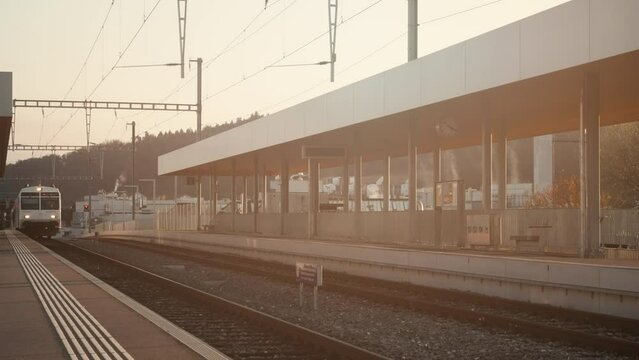 Switzerland public transport train arriving at outdoor station during golden hour
