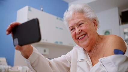 Happy senior woman with bandage on arm after vaccination taking selfie in doctor's office. - Powered by Adobe