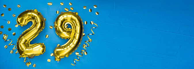 golden foil balloon number twenty nine. Birthday or anniversary card with the inscription 29. blue concrete background. Anniversary celebration. Banner.