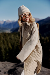 young woman in autumn clothes stands on a rock landscape blue sky lifestyle