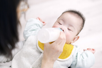 寝ながらミルクを飲むアジア人の赤ちゃん