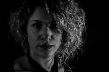 Black and white portrait of a beautiful curly blonde woman who is looking seriously in front of her