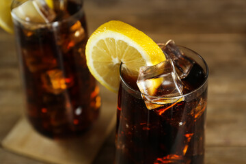 Glasses of refreshing soda water with ice cubes and lemon slices on table, closeup