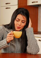 Young latin woman drinking coffee,blowing cup.