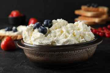 Tasty cream cheese and fresh berries on black table