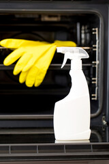 On the door of an open oven is a mock-up of a white spray bottle with oven detergent. General cleaning of the kitchen.