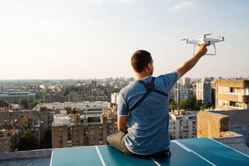 Young technician flying UAV drone with remote control on rooftop