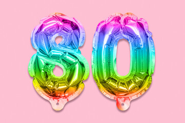 Rainbow foil balloon number, digit eighty on a pink background. Birthday greeting card with inscription 80. Anniversary concept. Top view. Numerical digit. Celebration event, template.