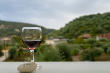 Glass of red wine on background of beautiful green mountains view,landscape. Concept of lifestyle, savoir-vivre, relax or having rest