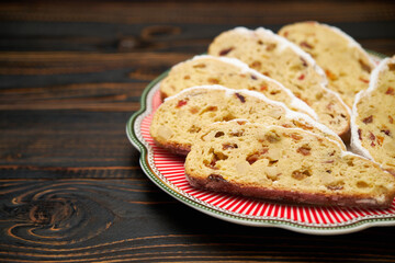 Slices of Traditional Christmas stollen cake with marzipan and dried fruit on wooden background