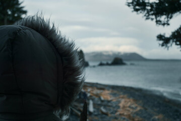 Person in hood looking out to the cold beach in Alaska.
