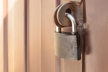 Close-up padlock on the gate of a metal brown fence made of modern siding, the concept of security
