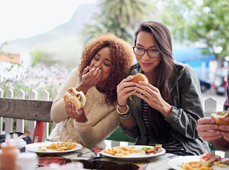 This is the best place in town. Cropped shot of a friends eating burgers outdoors.