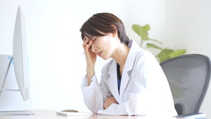 頭を抱えて悩む日本人女性医師 - obrazy, fototapety, plakaty