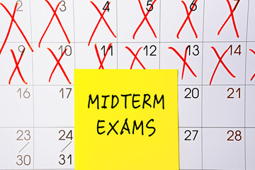 The phrase Midterm exams written on a yellow sticky note posted on a calendar or planner page as a...