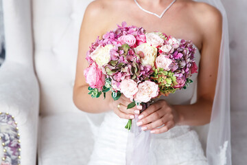 Obraz na płótnie Canvas the bride in a white slinky dress holds a wedding bouquet of pink peonies