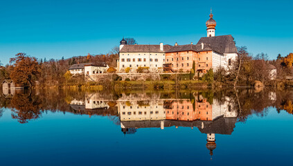 Fototapeta na wymiar Beautiful indian summer view with reflections and a monastery at the famous Hoeglwoerther See lake, Bavaria, Germany