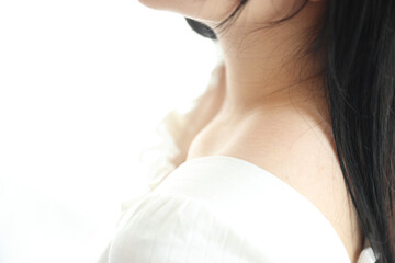 Close up of shoulder young Asian woman on bed relaxing in the morning light with white room