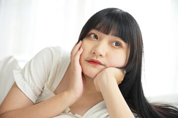 Fototapeta premium Beautiful young Asian woman sleeping on bed relaxing in the morning light with white room