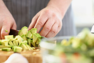Man cutting mellow avocado on cutting board, inspiration to cook tasty dinner