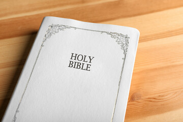 Bible with white cover on wooden table, closeup