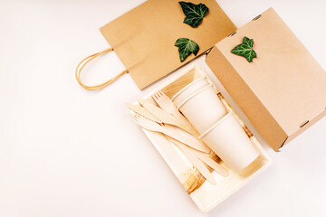 Eco craft paper tableware,cups,fast food containers.Recycling,eco-friendly concept.Disposable eco cutlery,plates,spoons,knives,forks on a light background.Craft paper bag for food delivery.Copy space.