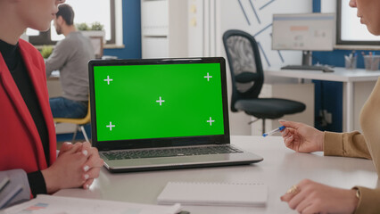 Close up of colleagues using laptop with green screen on desk, women working with isolated template, mock up background and chroma key on display. Computer with chroma-key copy space