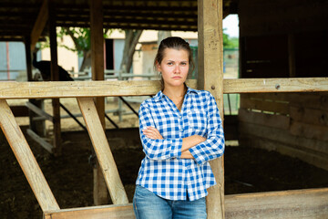 Upset female farmer standing outdoors near empty stall, having problems on her farm