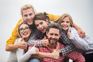 Obraz premium Happy company students best friends making selfies. Group young people posing together with thumb up. Multi ethnic business team. Smiling group of friends laughing.