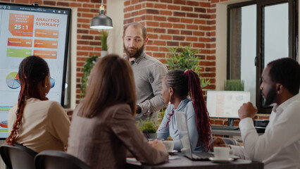 Business man presenting financial analysis and statistics o display to workmates at briefing meeting. Worker doing presentation to work on project planning and marketing strategy in office.
