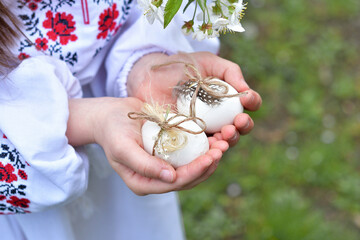 Happy easter day. caucasian girl holding colored eggs .girl in a traditional embroidered shirt in a...