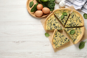 Cut delicious spinach pie with ingredients on white wooden table, flat lay. Space for text