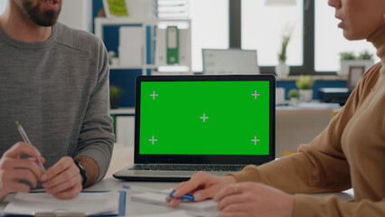 Close up of people working with green screen on laptop in startup office. Man and woman using chroma key copy space with isolated mock up template and blank background on display.