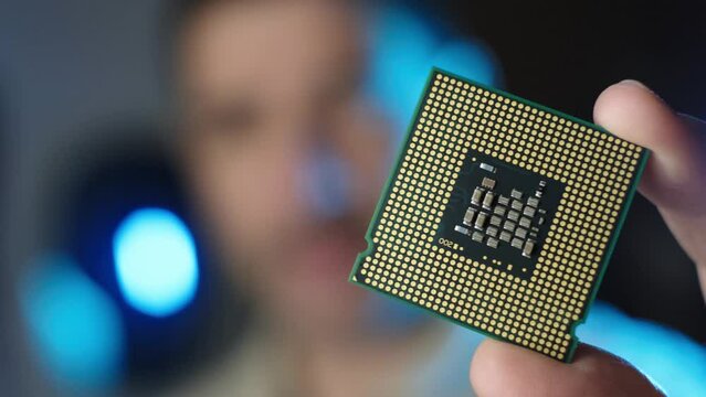Male technician holds in hand CPU processor, Integrated circuits microchips concept, Blurred background