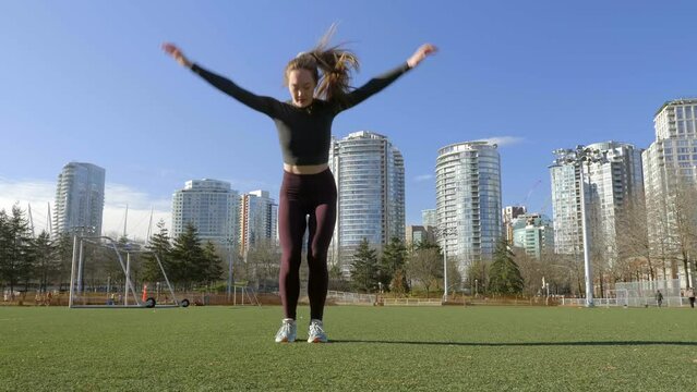Fit young woman doing burpees bodyweight exercise in park