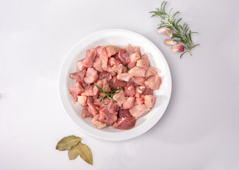 Fototapeta na wymiar Diced meat on a white plate, isolated. Raw poultry, pork meat in cubes and seasonings, on white background.