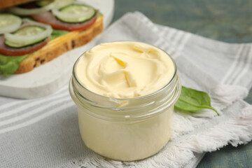 Fototapeta na wymiar Jar of delicious mayonnaise and napkin on light blue wooden table