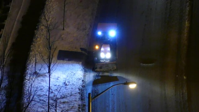 High Angle View Of A Snowplow Tractor Driving On The Road Late At Night In Winter.