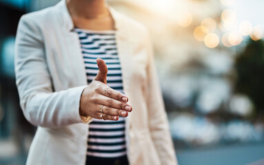 Making deals throughout the city. Closeup shot of an unrecognizable businesswoman extending a handshake in the city.