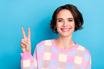 Photo of young pretty woman cheerful show fingers peace cool v-symbol isolated over blue color background